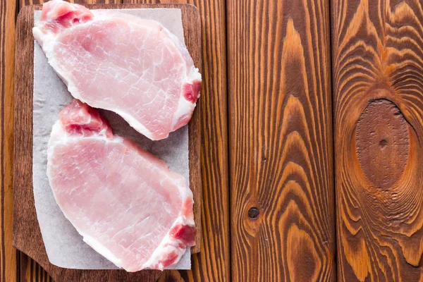 Daging babi mentah di papan potong pada latar belakang kayu — Stok Foto