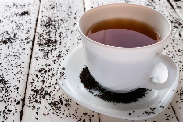 Tasse de thé sur un fond de feuilles de thé — Photo