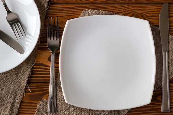 White empty plate with cutlery on a wooden background — Stock Photo, Image