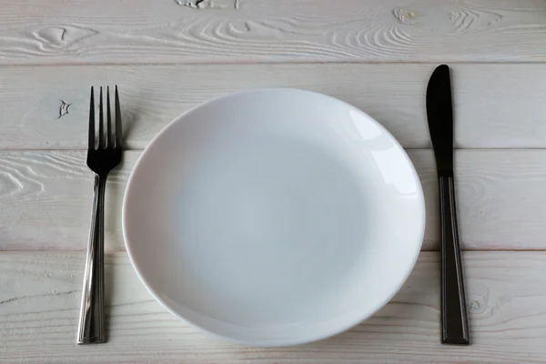Clean plates and cutlery on a wooden background — Stock Photo, Image