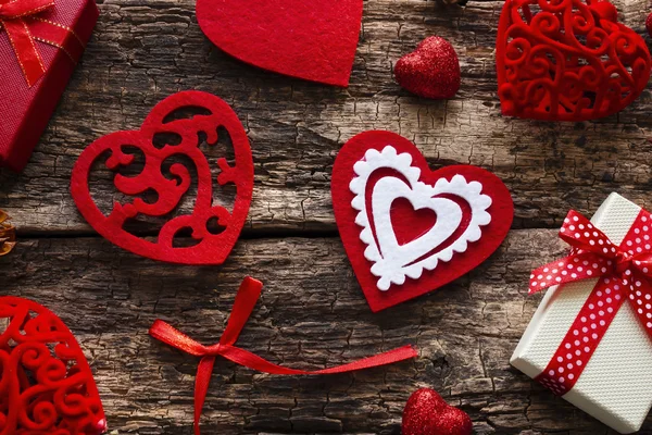 Presentförpackning, röda hjärtan och rosett på en trä bakgrund — Stockfoto