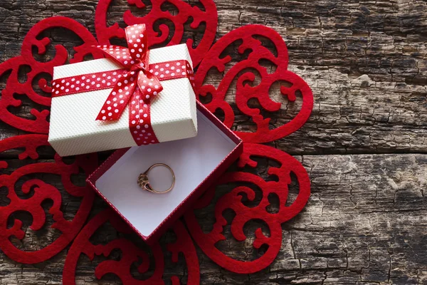 Boîte cadeau avec une bague de mariage à l'intérieur d'un motif de cœurs rouges — Photo