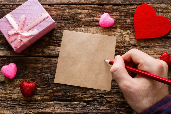 Man skriver en kärlek anteckning på en trä bakgrund — Stockfoto