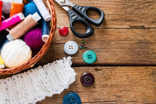 корзина с ниткой и пряжей на деревянном фоне
