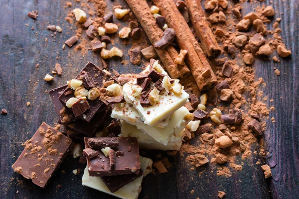 Pila de chocolate con nueces ralladas y cacao sobre un fondo negro — Foto de Stock