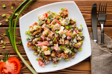 çatal bıçak takımı, yeşil soğan ve domates yarısı yanında beyaz bir tabak salata