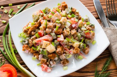 yeşil soğan ve domates çatal yanındaki bir masada beyaz bir tabak içinde taze sebze salatası