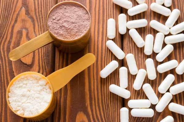 Capsules van creatine en proteïne meten lepels op een houten achtergrond — Stockfoto