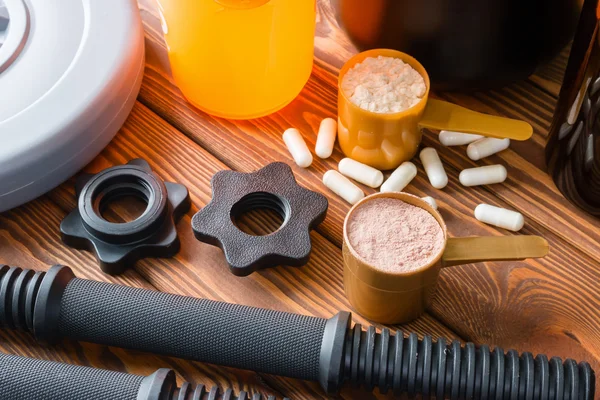 plastik damga ve Spor beslenme shaker ahşap arka plan üzerinde halter