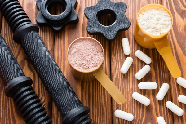 Dumbbell neck and measuring spoons with protein closeup — Stock Photo, Image