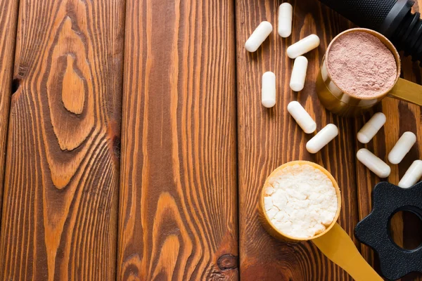 Спортивное питание и гантели на деревянном фоне — стоковое фото