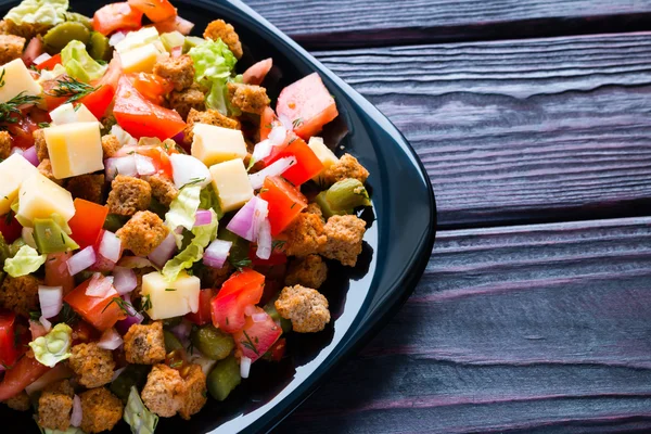 Salad vegetarian dengan sayuran, keju dan kerupuk dengan latar belakang hitam — Stok Foto