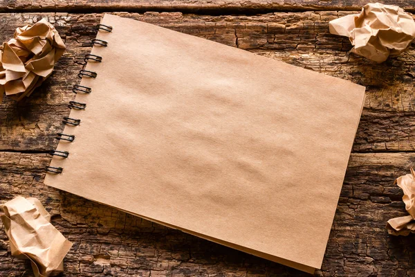 Notebook and crumpled paper on a wooden table — Stock Photo, Image