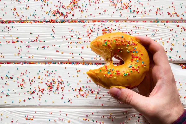 man holding bitten donut on a white background