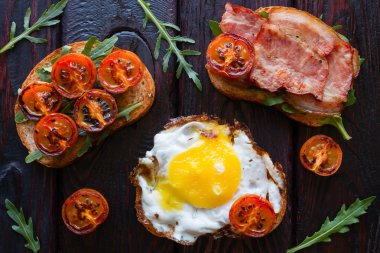 lezzetli sandviçler siyah bir zemin üzerine Közlenmiş domates ve roka ile dekore edilmiş