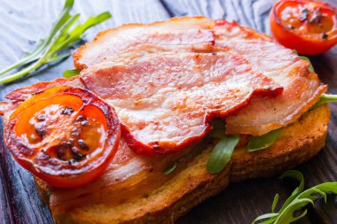 Kızarmış domuz pastırması, domates ve roka ile sandviç