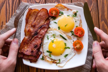 adam onun kahvaltı pişmiş yumurta, domuz pastırması ve domates yeme