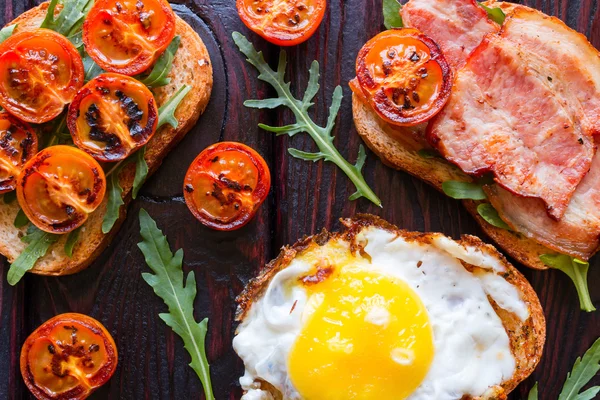 sandviç siyah bir zemin üzerine Közlenmiş domates ve roka yakın çekim dekore edilmiş