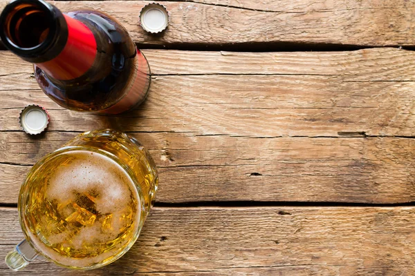 Garrafa de vidro e uma caneca de cerveja leve em um espaço de fundo de madeira para texto — Fotografia de Stock