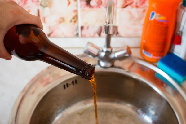 L'uomo versa la birra nel lavandino fuoco selettivo — Foto Stock