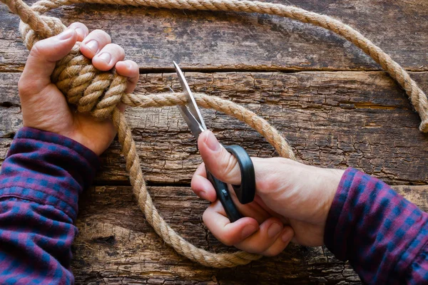 Hombre cortar la cuerda con un concepto de nudo resbaladizo detener el suicidio — Foto de Stock