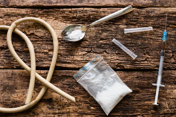 Viciado em acessórios - torniquete, colher, seringa, uma droga no fundo de madeira — Fotografia de Stock