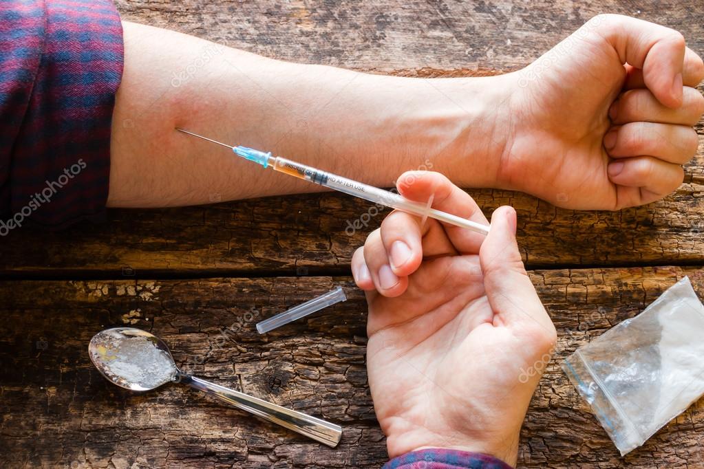 male drug addict injects himself a dose of the drug selective focus