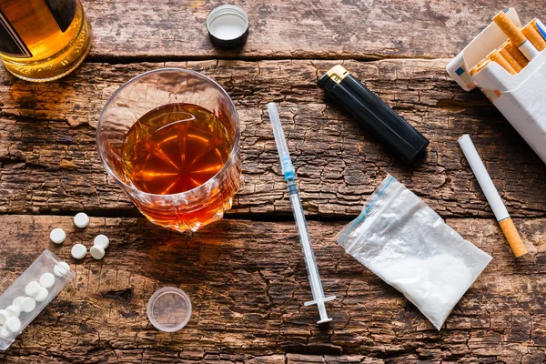 Álcool, cigarros, drogas, pílulas em um fundo de madeira — Fotografia de Stock