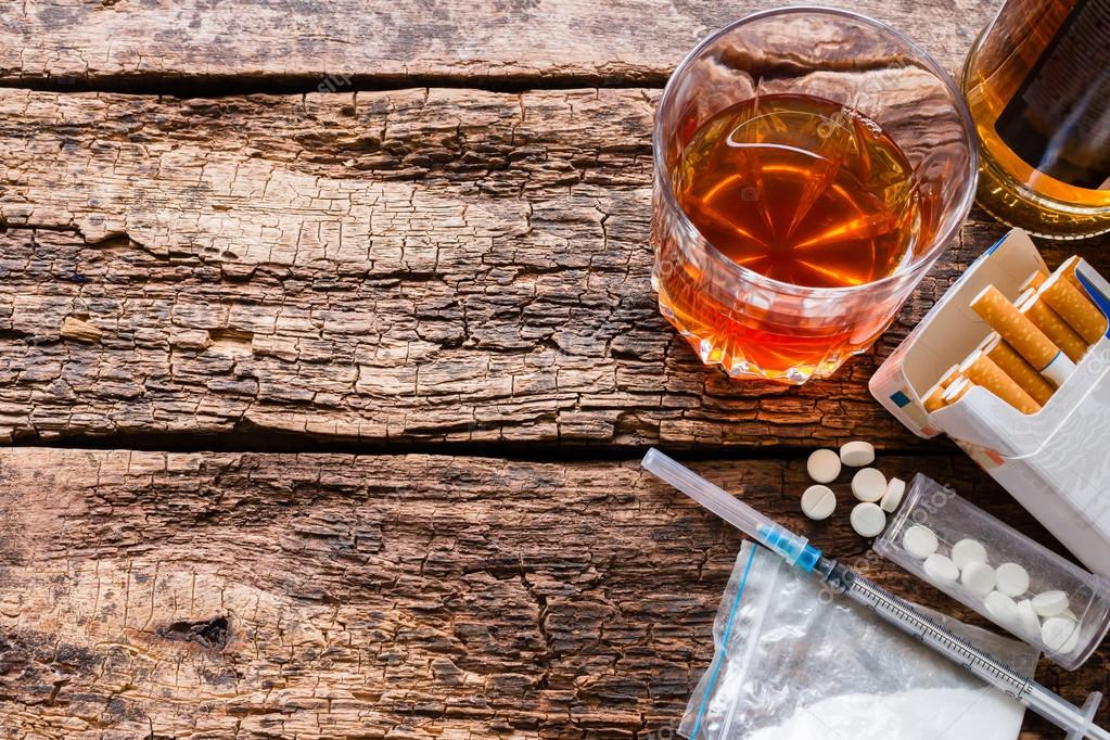 Alcohol, cigarettes and drugs on wooden background template space for