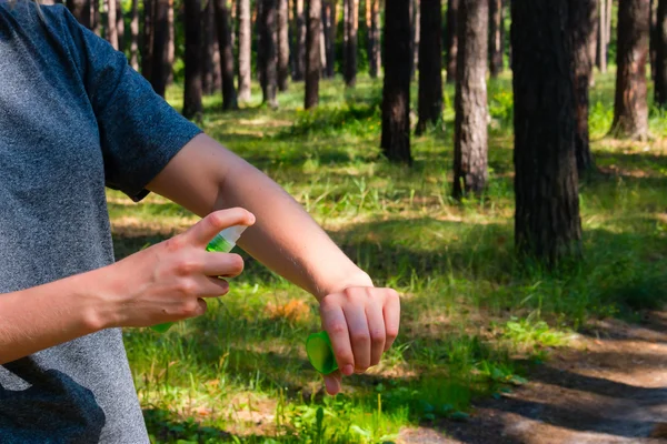 Menina na floresta usa o spray contra mosquitos — Fotografia de Stock