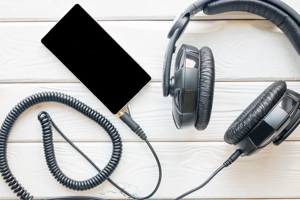 Auriculares negros y teléfonos inteligentes en una maqueta de fondo blanco — Foto de Stock