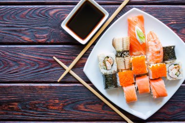 Beyaz bir tabak ve yemek çubukları üzerinde suşi rulo