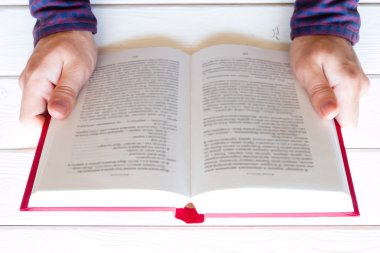 Beyaz ahşap arka plan seçici odak üzerine bir kitap okurken erkek