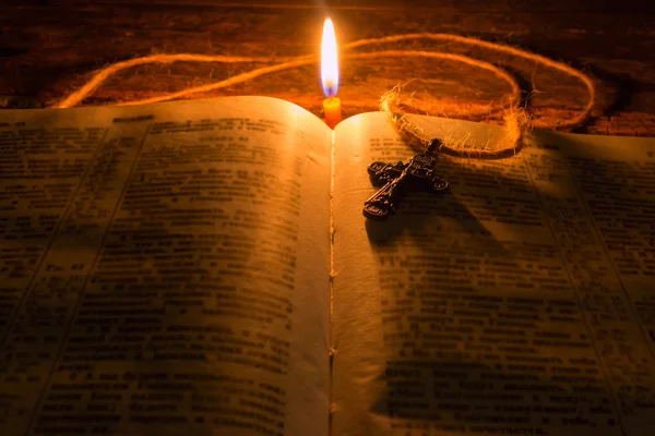 Cross on the Bible by candlelight selective focus — Stock Photo, Image