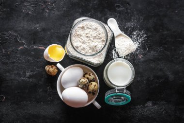 Siyah arkaplanda pişirme malzemeleri, süt, yumurta, un