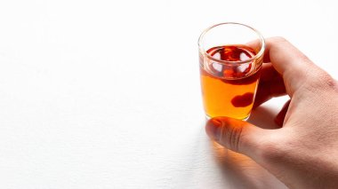 Elinde beyaz bir arka planda alkollü bir bardak ve yakın çekim için bir yer tutuyor.