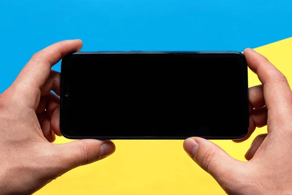 holding a smartphone with a black screen with a place for text mockup