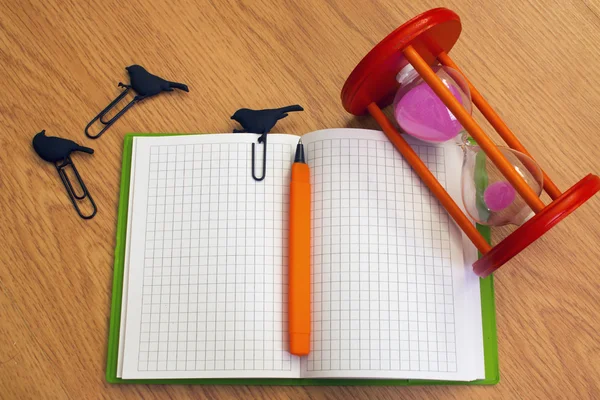 Caneta de ampulheta de caderno e clipes na mesa — Fotografia de Stock