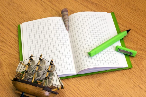 Notebook with green pen and seashells on the desk — Stock Photo, Image