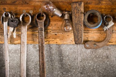 Rusty wrenches, adhesive tape, an awl, a light bulb, a collar on an old wooden stand