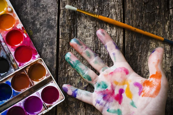 Pincel de pintura acuarela para pintar la mano del artista en pintura multicolor sobre fondo de madera — Foto de Stock