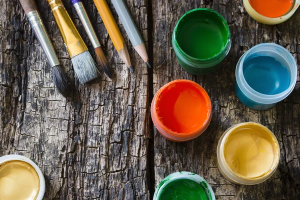 Pintura de pincel, lápices cincelados, pintura gouache en una vieja mesa de madera — Foto de Stock