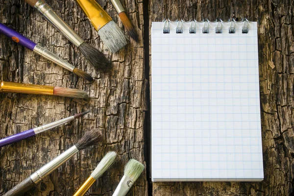 Brushes for painting in a semicircle, notes on old wooden table mock up — Zdjęcie stockowe