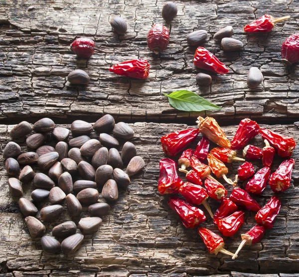 The heart of the dry red pepper, pine nuts, dogrose on a wooden background — Stock Photo, Image