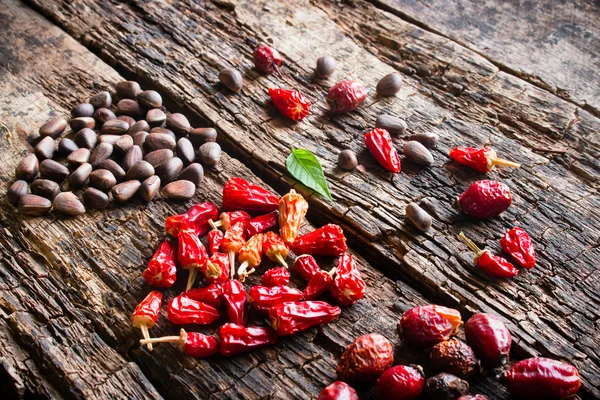 The heart of the dry red pepper, pine nuts, dogrose on wooden background side view selective focus — Stock Photo, Image