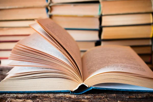 Opened old book on the background of the stack of books — Stockfoto