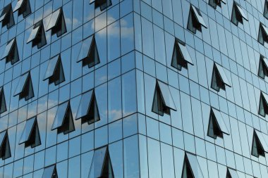 Cam ofis binasının güzel arka planı, açık pencerelerdeki bulutları yansıtıyor.