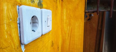 Kullanılmayan eski binanın sarı duvarındaki soket. Sarı duvarda elektrik düğmesi