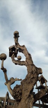 Bulutlu mavi gökyüzü arka planında eski ahşap ağaçtaki kuş evi