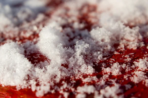 Neve close-up em um fundo de madeira vermelho — Fotografia de Stock